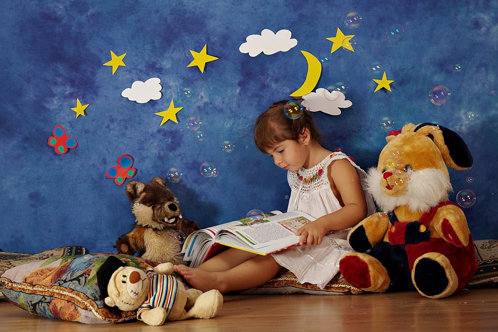 Enfant lisant un livre avec ses amis / CC BY 3.0 Nicu Buculei